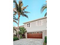 Two-story home with a paver driveway, garage, palm trees, and light gray siding at 7551 141St St, Seminole, FL 33776