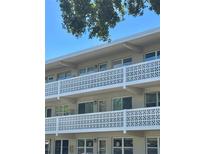 White condo building featuring three floors and decorative concrete block balcony railings under a blue sky and tree canopy at 8100 Dr Martin Luther King Jr N St # 302, St Petersburg, FL 33702