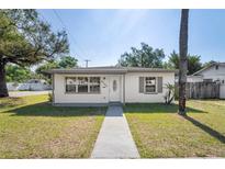 Charming single-story home featuring a well-manicured lawn, concrete walkway, and bright exterior paint at 8725 N Boulevard, Tampa, FL 33604