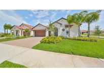 Beautiful single-story home showcasing a well-manicured lawn, palm trees and a two-car garage at 17152 Scuba Crest St, Wimauma, FL 33598