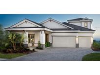 Inviting home featuring a manicured lawn, gray brick driveway, and a three-car garage at 17716 Roost Pl, Lakewood Ranch, FL 34211