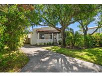 Charming single-story home featuring a red tile roof, complemented by mature trees and lush landscaping at 409 Erie Ave, Tampa, FL 33606