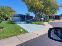 Charming home featuring a painted driveway, mature tree, and well-maintained landscaping at 46 Washington Ct # 28, Palm Harbor, FL 34684