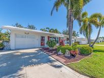 Charming single-story home featuring a well-manicured lawn, mature palm trees, and tasteful landscaping at 14173 90Th Ave, Seminole, FL 33776