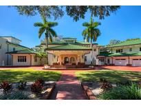 Stately home featuring lush landscaping, palm trees, and a grand entrance with a portico and green tile roof at 802 Druid S Rd, Clearwater, FL 33756