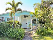 Charming blue home featuring a lush garden, mature palm trees, and a welcoming front porch at 4038 2Nd N Ave, St Petersburg, FL 33713