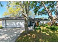 Charming single-story home featuring an attached two-car garage and beautifully landscaped front yard with mature trees at 4915 Churchill Pl, Land O Lakes, FL 34639