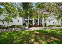 Beautiful white condominium building exterior with tropical landscaping and a manicured lawn at 50 Harbor View Ln # 21, Belleair Bluffs, FL 33770