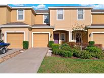 Charming townhome with well-maintained landscaping, tan siding, and attached garages at 7047 Towne Lake Rd, Riverview, FL 33578