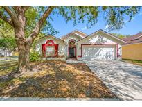 Charming single-Gathering home with white exterior, red trim, mature trees, and a two-car garage at 7116 Colony Pointe Dr, Riverview, FL 33578