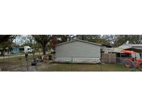 An exterior view of a mobile home and surrounding yard, with mature trees providing shade at 9907 Connecticut St, Gibsonton, FL 33534