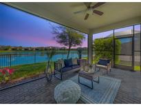 Relaxing covered patio with comfortable seating and a beautiful view of the lake at 30423 Ceasar Park Dr, Wesley Chapel, FL 33543