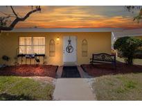 Charming yellow home featuring a decorative front door, cozy bench, and inviting, landscaped yard at 401 Dorchester Pl # 55, Sun City Center, FL 33573