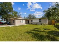 Inviting single-story home featuring a lush green lawn and a charming, neutral-toned exterior at 5208 S 82Nd St, Tampa, FL 33619