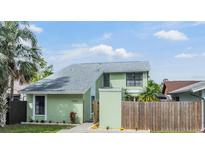 Charming two-story home with light green exterior, well-maintained landscaping, and a gray roof at 10306 Green Grove Pl, Tampa, FL 33624