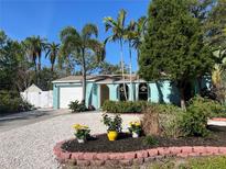 Charming home with a well-manicured front yard featuring tropical plants, flowers, and a white gravel driveway at 1754 Patricia Ave, Dunedin, FL 34698