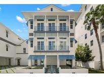 Elegant three-story home featuring balconies, blue awnings, and modern architectural design at 19 Somerset St, Clearwater Beach, FL 33767