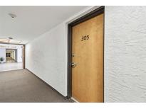 Hallway view leading to unit 305 featuring textured walls and an open doorway at the end of the hall at 2595 Countryside Blvd # 8-305, Clearwater, FL 33761