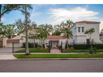Stately home featuring a tile roof, white stucco exterior, gated entrance, and meticulously landscaped front yard at 54 Aegean Ave, Tampa, FL 33606
