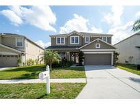 Two-story home features a well-manicured lawn, covered front porch, and attached two-car garage at 7653 Stoney Hill Dr, Wesley Chapel, FL 33545