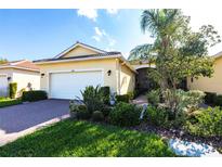 Inviting home featuring lush landscaping, a two-car garage, and a beautiful red brick driveway at 16106 Amethyst Key Dr, Wimauma, FL 33598