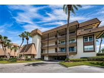 Attractive condominium complex featuring multiple stories, balconies, and lush landscaping with mature palm trees against a bright blue sky at 3021 Countryside Blvd # 26A, Clearwater, FL 33761