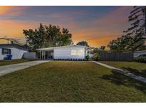 Charming single-story home with a well-manicured lawn and quaint carport against a colorful evening sky at 4030 Marlin Se Dr, St Petersburg, FL 33705