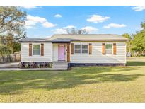 Charming single-story home with a well-manicured lawn, decorative shutters, and a cheerful pink front door at 501 W Bird St, Tampa, FL 33604