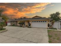 Charming home featuring a two-car garage and stone accents, set against a vibrant sunset at 1992 S Belcher Rd, Clearwater, FL 33764