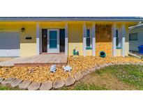 Charming yellow home featuring a stone facade, decorative rocks, and turtle lawn ornaments at 5427 Springwood Blvd # 5427, Pinellas Park, FL 33782