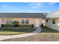 Charming single-story home featuring a metal roof, manicured lawn, and inviting walkway at 11719 Boynton Lane, New Port Richey, FL 34654