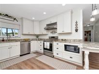 Bright kitchen features white cabinets, granite countertops, stainless steel appliances, and hardwood floors at 13596 Croft N Dr, Largo, FL 33774