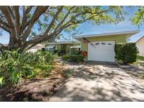 Charming single-story home featuring mature trees, landscaped yard and a two-car garage at 1521 San Helen Dr, Dunedin, FL 34698