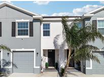 Charming townhome featuring a one-car garage, gray and white stucco, and well-maintained landscaping at 16646 Maude Dr, Wimauma, FL 33598