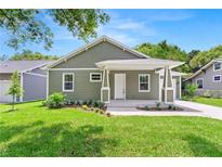 Charming home with a covered front porch, green siding, and landscaped front yard at 9303 N 19Th St, Tampa, FL 33612