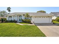 Charming one-story home with lush lawn, mature landscaping and a driveway leading to an attached two-car garage at 13553 Landers Dr, Hudson, FL 34667