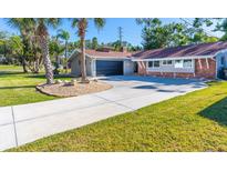 Charming home showcasing a well-manicured lawn, palm trees, and a long driveway leading to a two-car garage at 2096 Church Creek Pt, Largo, FL 33774