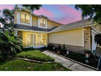 Charming two-story home featuring yellow siding, a screened-in porch, and landscaped front yard at 2199 Springrain Dr, Clearwater, FL 33763