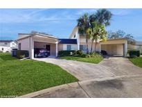 Charming home featuring a spacious driveway, carport, and lush landscaping with mature palm trees at 2572 Forest Run Ct, Clearwater, FL 33761