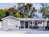 Charming single-story home with blue front door, manicured lawn and welcoming front porch with chairs at 314 E Althea Ave, Tampa, FL 33612