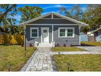 Charming gray home featuring new landscaping, a paved walkway, and a well-manicured lawn at 5108 N Suwanee Ave, Tampa, FL 33603