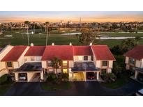 A townhouse with a red roof and two carport spaces overlooks a golf course and a skyline in the distance at 6140 Sun Blvd # 7, St Petersburg, FL 33715