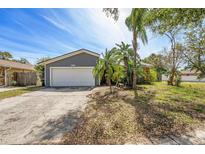 Charming single Gathering home with a large garage, lush landscaping, and mature palm trees at 1366 Wexford N Dr, Palm Harbor, FL 34683