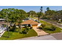 A single-story home with a brown roof, brick driveway, and lush green lawn surrounded by trees at 1591 N Dakota Ne Ave, St Petersburg, FL 33703