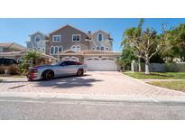 Charming two-story townhome with a well-manicured lawn and a spacious two-car garage and red paved driveway at 1806 Lago Vista Blvd, Palm Harbor, FL 34685