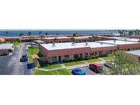 Aerial view showcases the condo community with covered parking, lush landscaping, and views of the waterfront at 19029 Us Highway 19 N # 27A, Clearwater, FL 33764