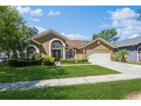 Charming single-story home with well-manicured lawn, mature trees, and a two-car garage at 3627 Cypress Meadows Rd, Tampa, FL 33624