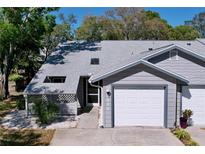 Charming gray home featuring an attached one car garage and well manicured landscaping at 39650 Us Highway 19 N # 411, Tarpon Springs, FL 34689