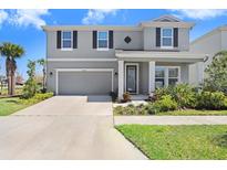 Charming two-story home featuring a manicured lawn, attached garage, and covered front porch with stately columns at 5407 Tagalong Pl, Apollo Beach, FL 33572