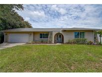 Charming home features a well-manicured lawn, stone accents, and an arched entryway leading to a white front door at 12299 91St N Ave, Seminole, FL 33772